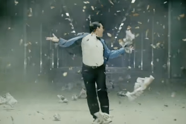 PSY walking through debris being blown his way